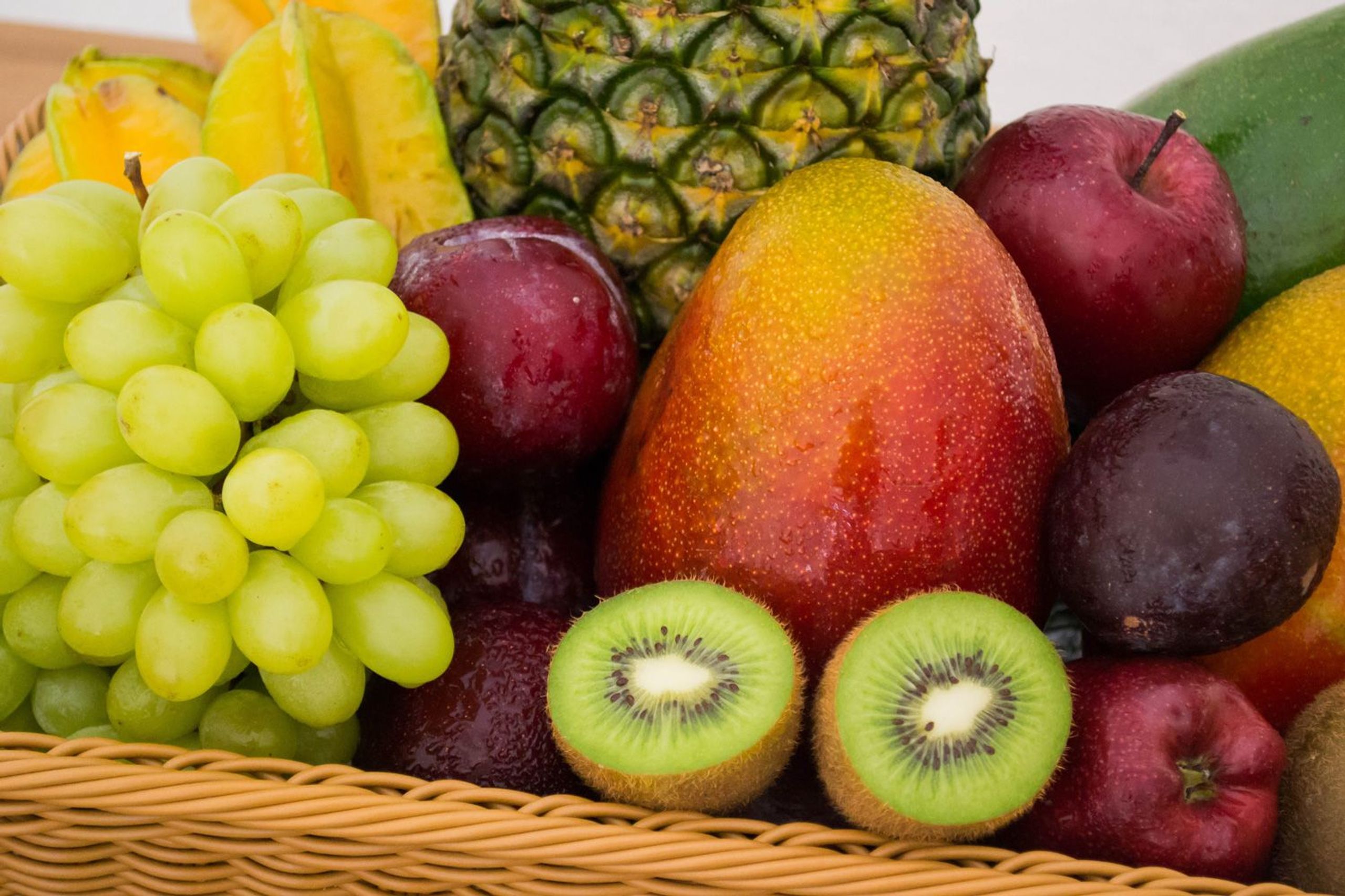 Obstkorb mit diversem Gemüse wie Kiwi, Mango, Apfel, Weintrauben und Ananas
