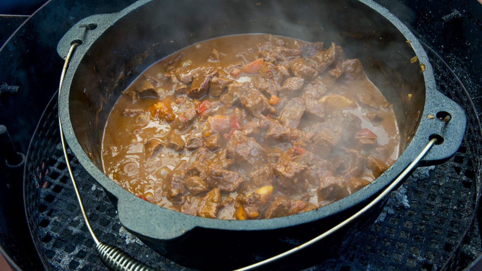 Gulasch im Dutch Oven auf Grillgitter mit Briketts