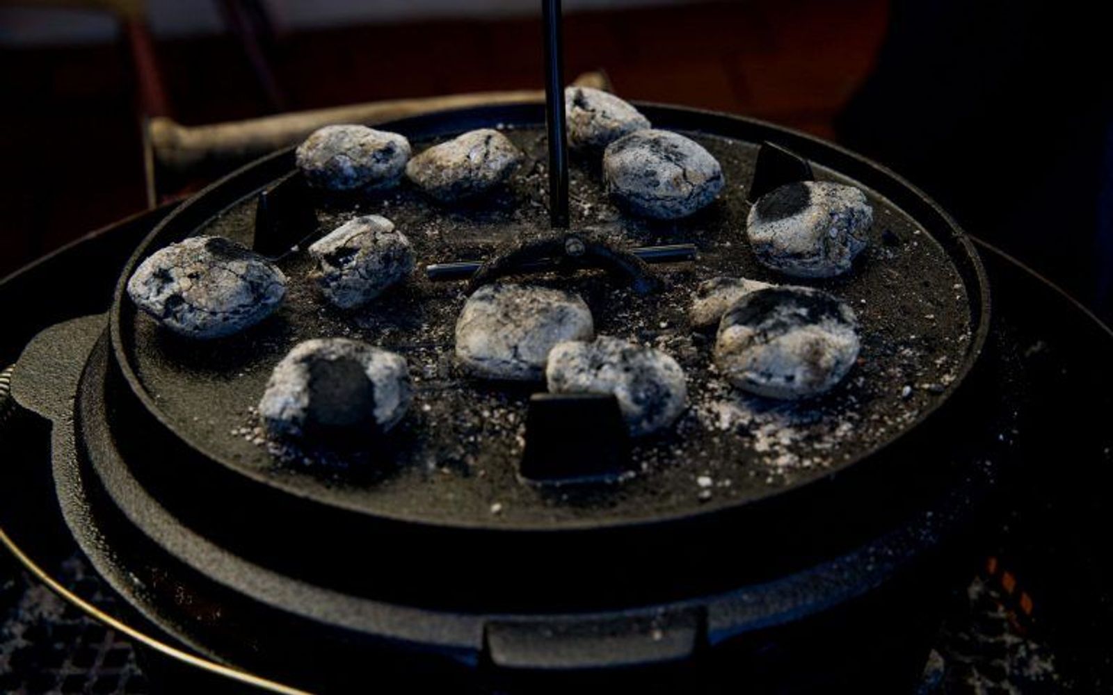 Glühende Briketts und Deckelheber auf Dutch Oven