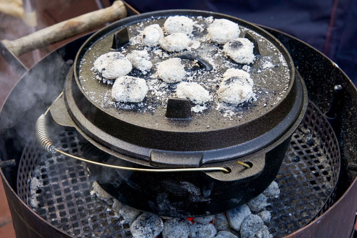 Dutch Oven auf Grillgitter mit glühenden Briketts