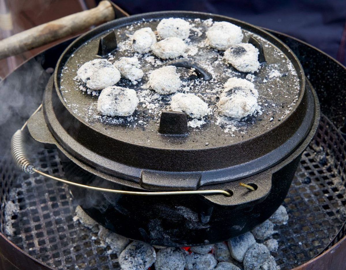 Dutch Oven auf Grillgitter mit glühenden Briketts