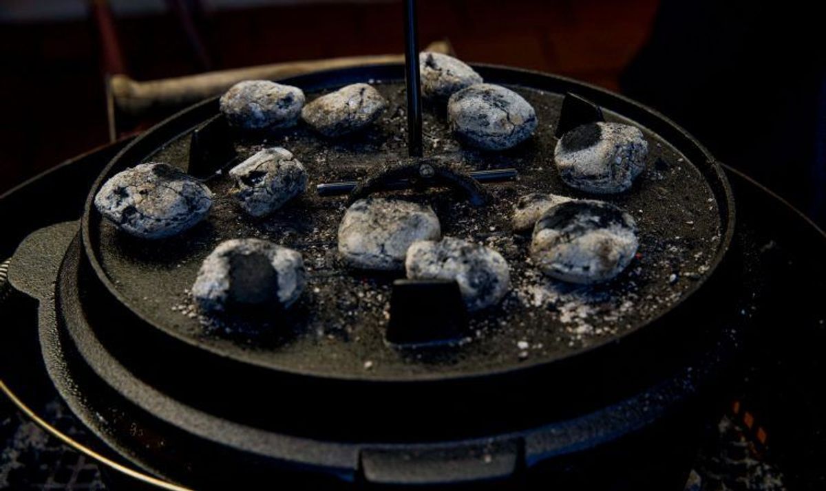 Glühende Briketts und Deckelheber auf Dutch Oven