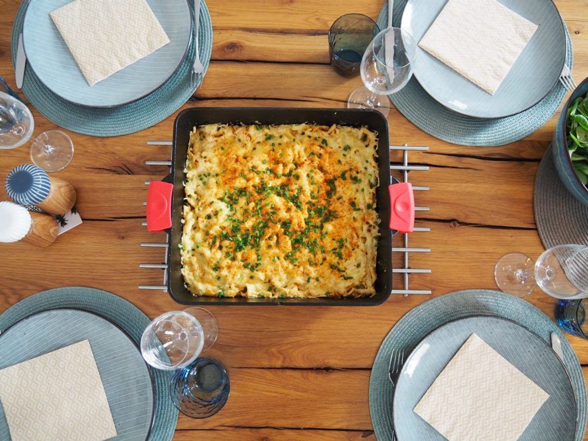 Dutch Oven Käsespätzle serviert auf Tisch mit vier Tellern