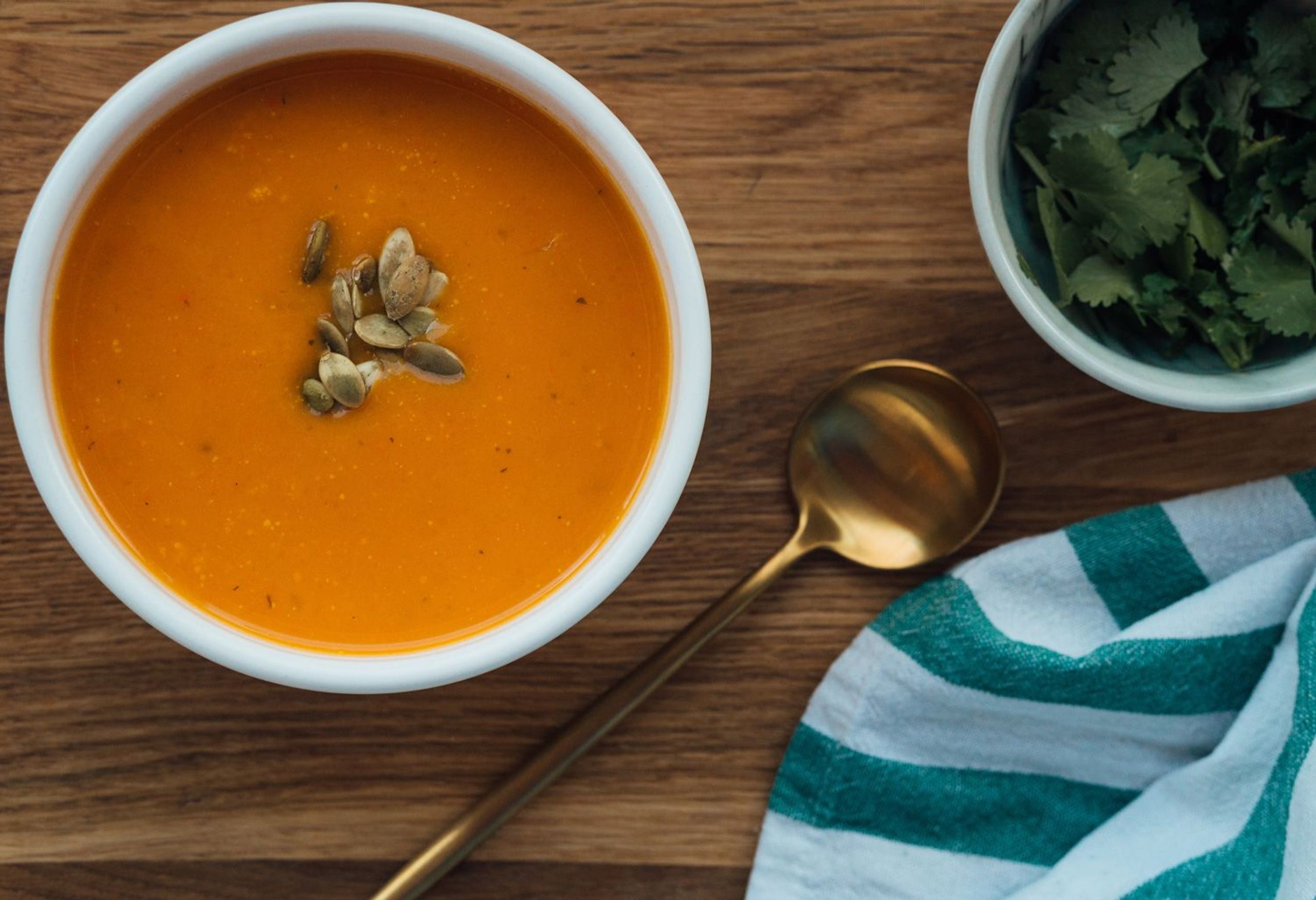 Möhren-Ingwer-Suppe in Schüssel serviert mit goldenem Löffel