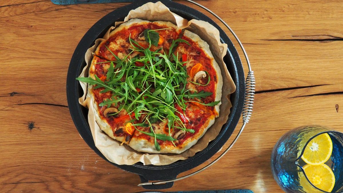 Vegetarische Dutch Oven Pizza aus dem Backofen auf Holztisch