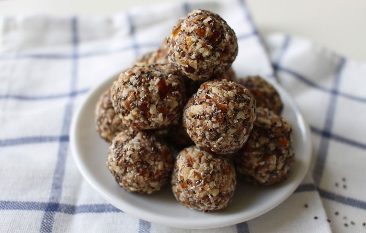 Energy Balls auf einem kleinen weißen Teller mit kariertem Geschirrtuch unter dem Teller