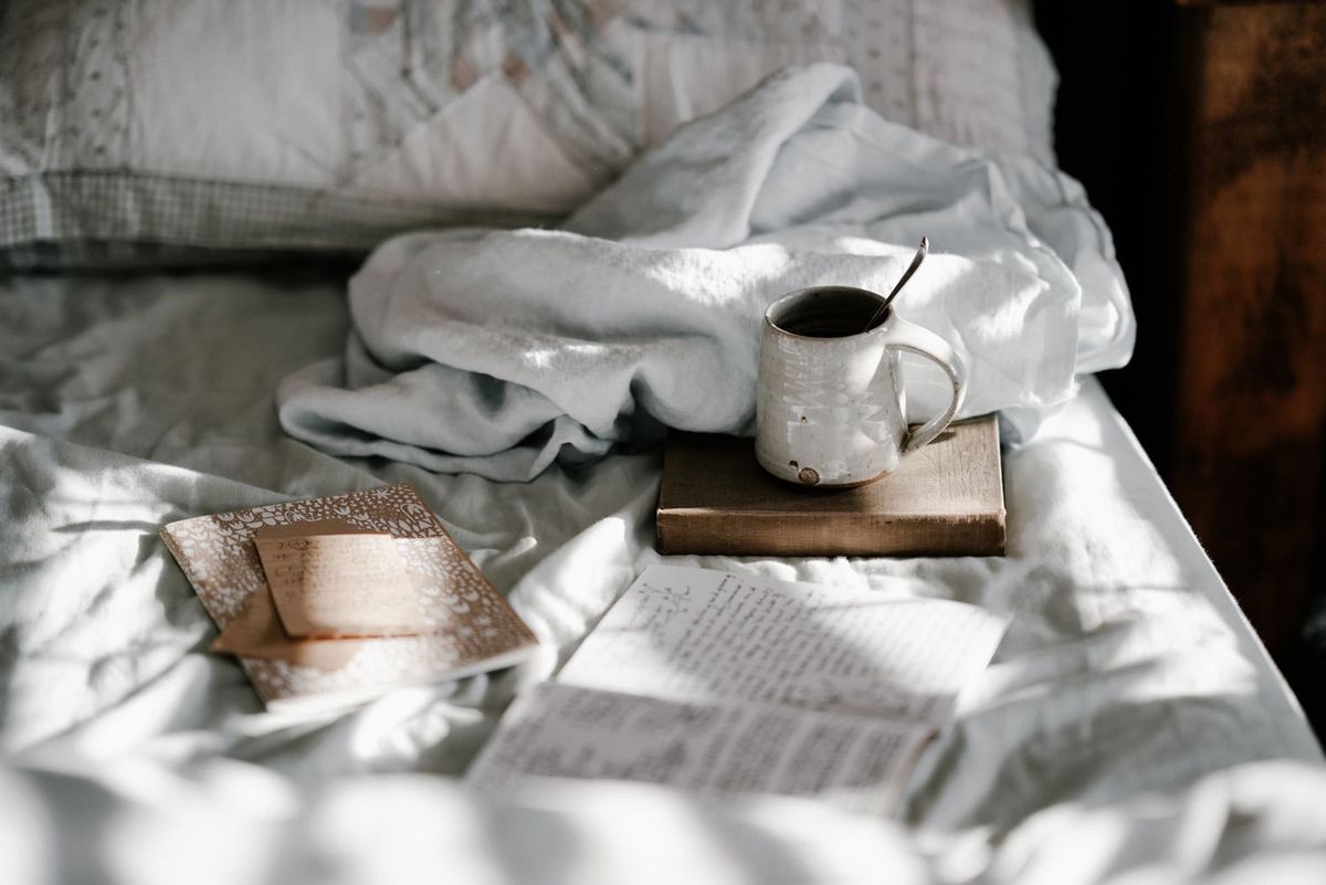 Bett mit Tasse Tee und Büchern und Notizheften