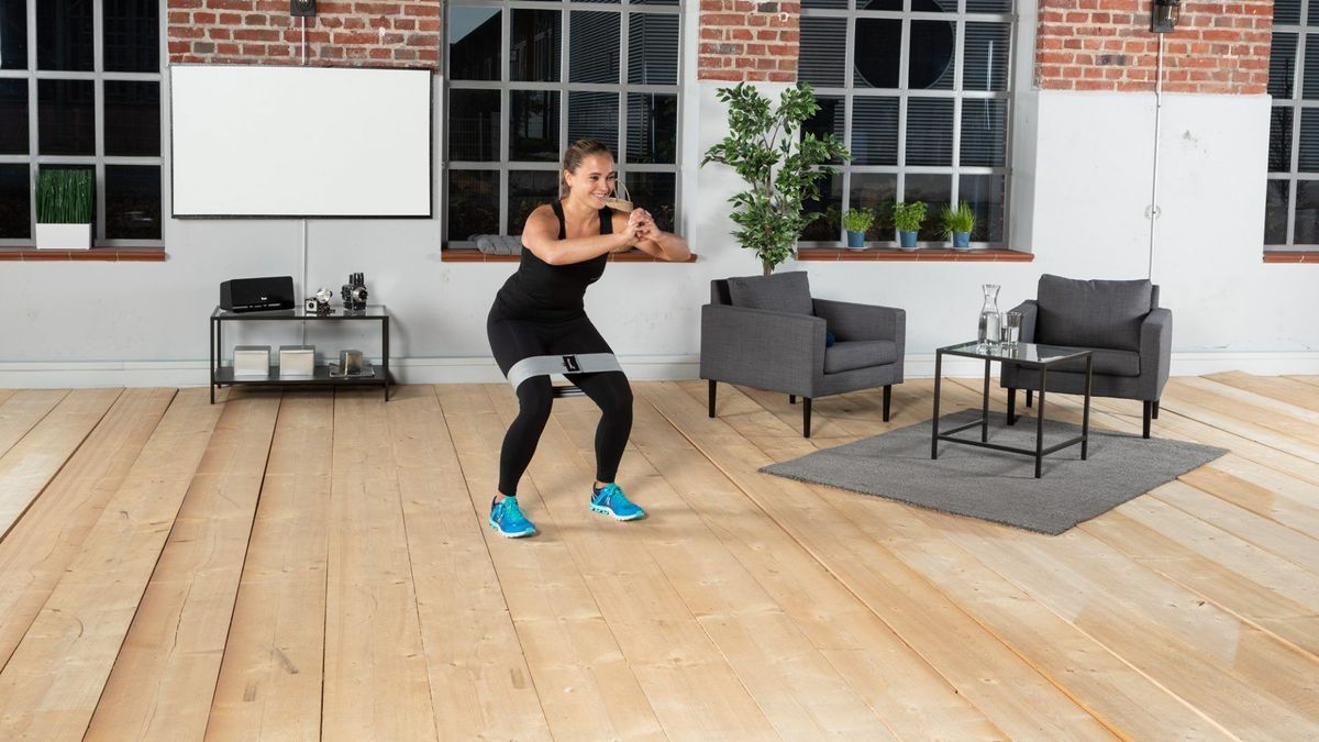 Sportlerin bei Squats mit Fitnessbändern in Setting