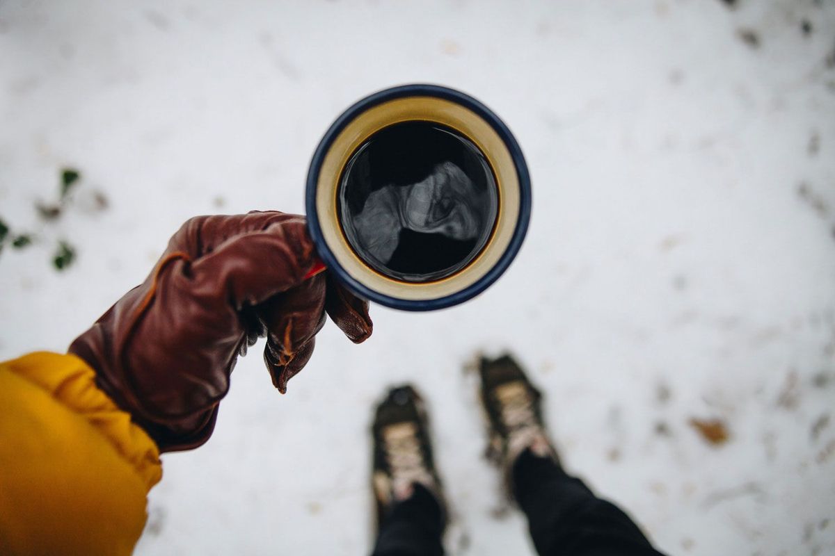 Tasse im Fokus von oben fotografiert mit schneebedecktem Boden im Hintergrund