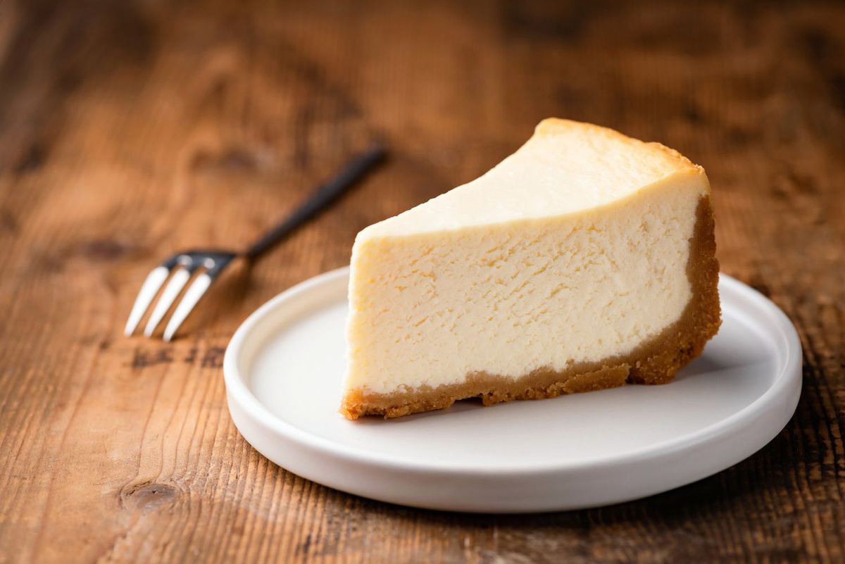 Weißer Teller mit Käsekuchen aus dem Dutch Oven auf Holztisch