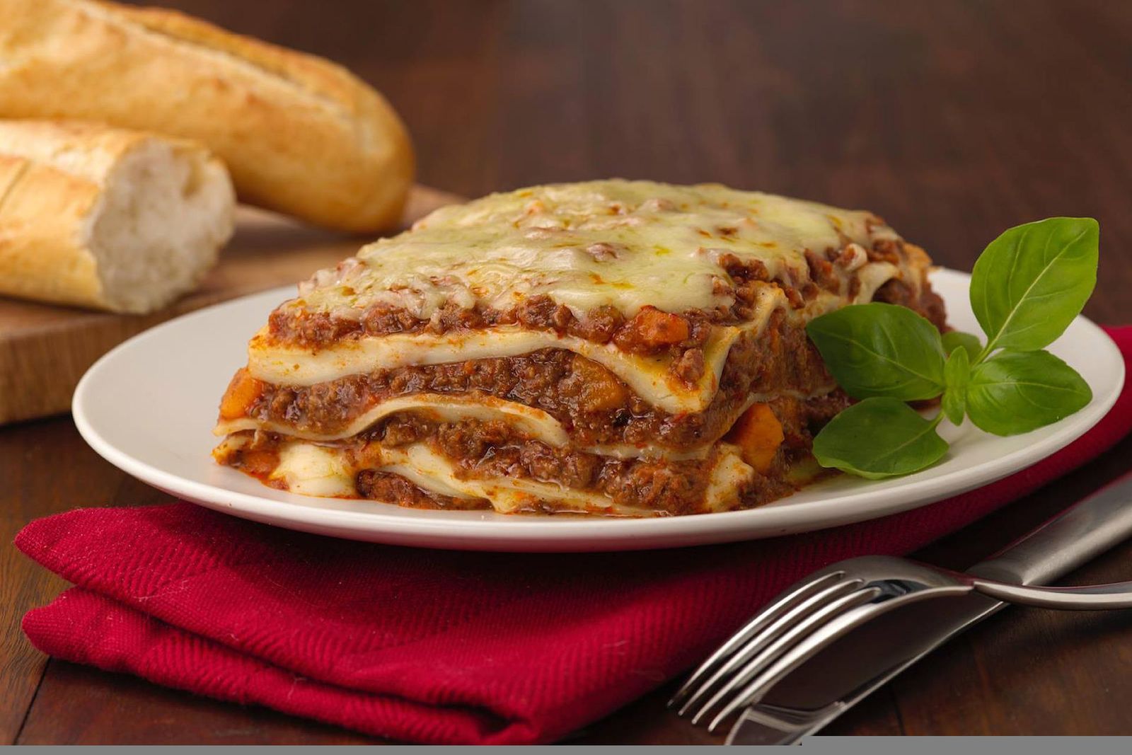 Dutch Oven Lasagne serviert auf weißem Teller mit Besteck