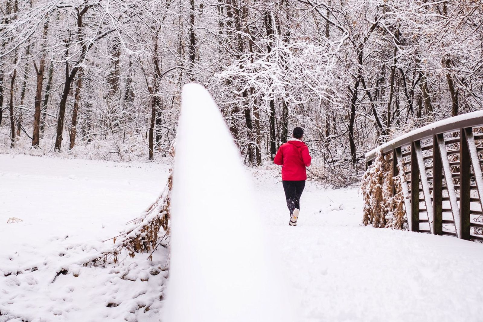 Jogger mit roter Jacke auf einer Brücke im Schnee