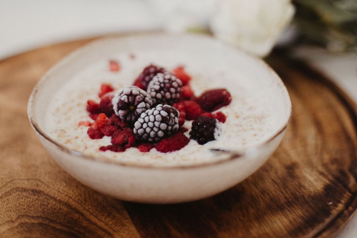 Joghurt mit Beeren in einer Schüssel auf einem Holzbrettchen