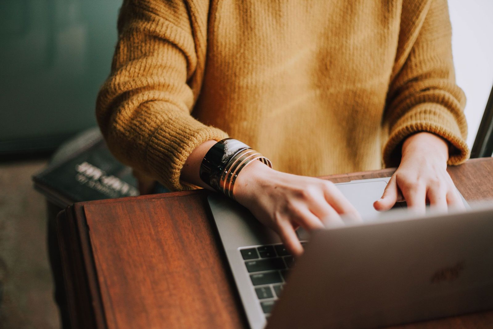 Frau mit gelbem Pullover beim Arbeiten am Laptop im Home Office