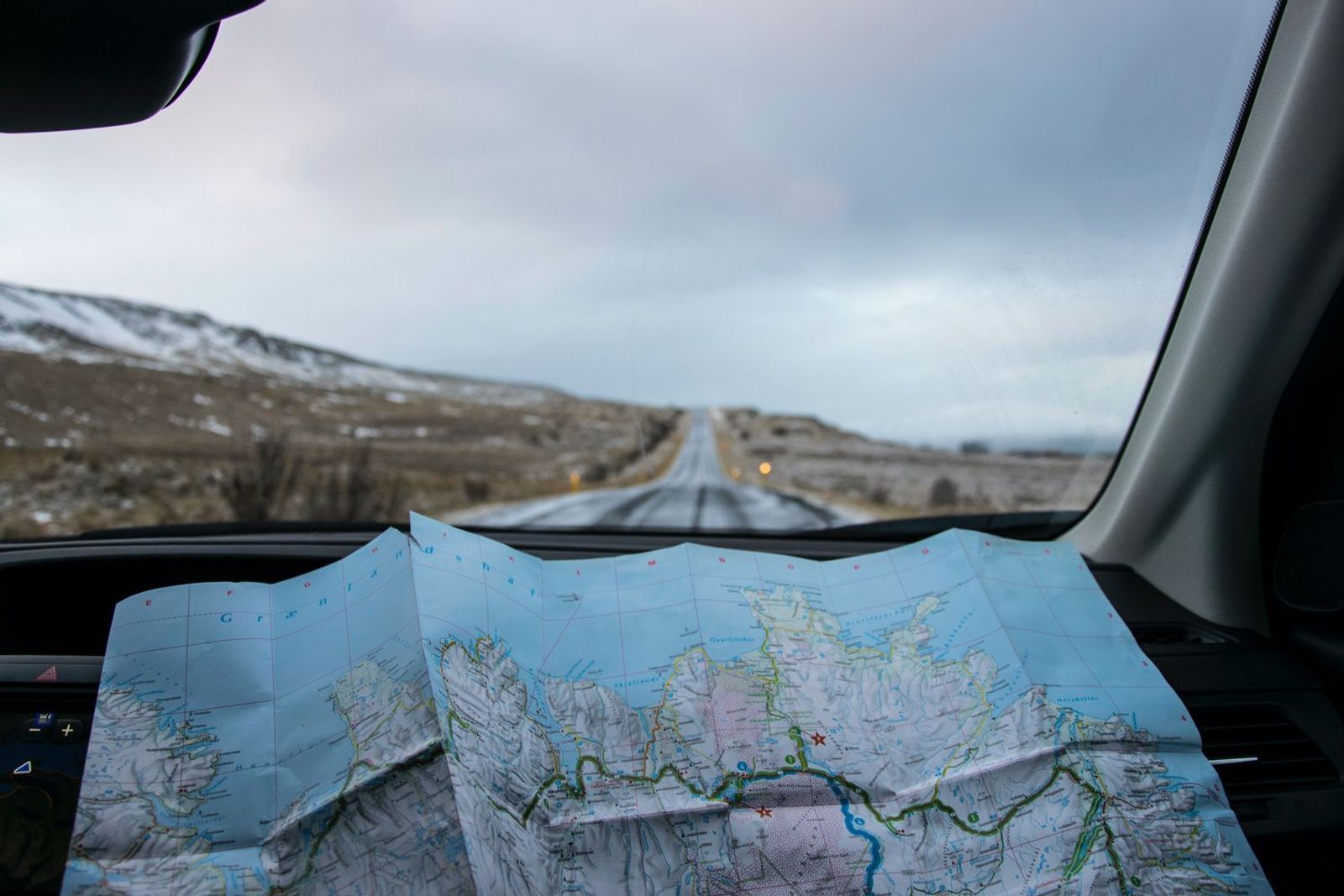 Landkarte ausgebreitet im Auto mit Landschaft im Hintergrund