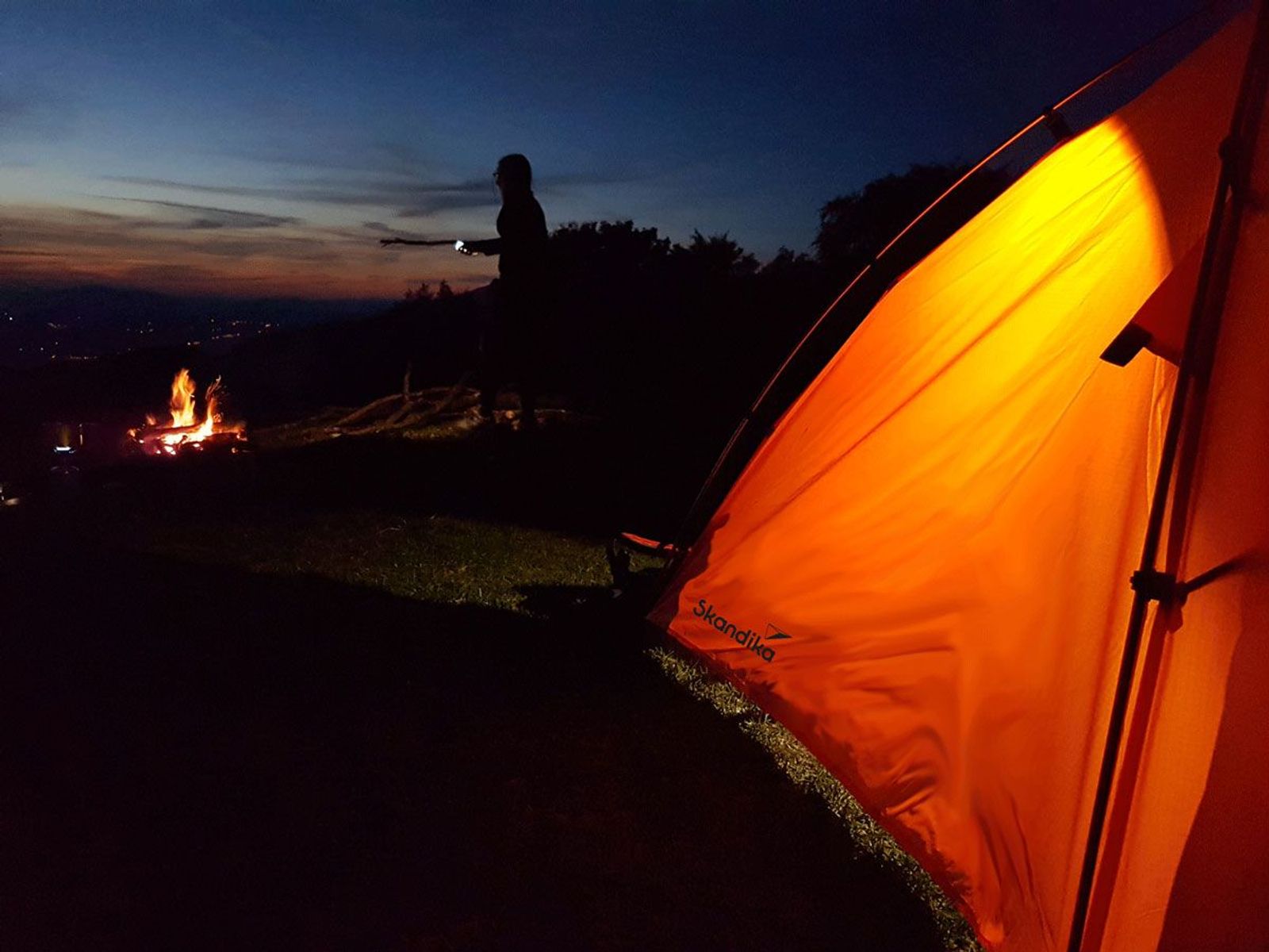 Beleuchtetes Zelt im Dunkeln mit nahegelegenem Lagerfeuer