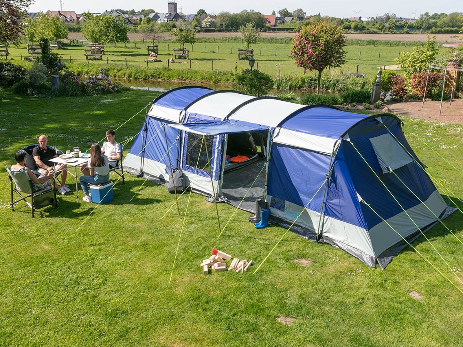 Steilwandzelt Montana 12 Sleeper aufgebaut im Grünen bei Sonnenschein