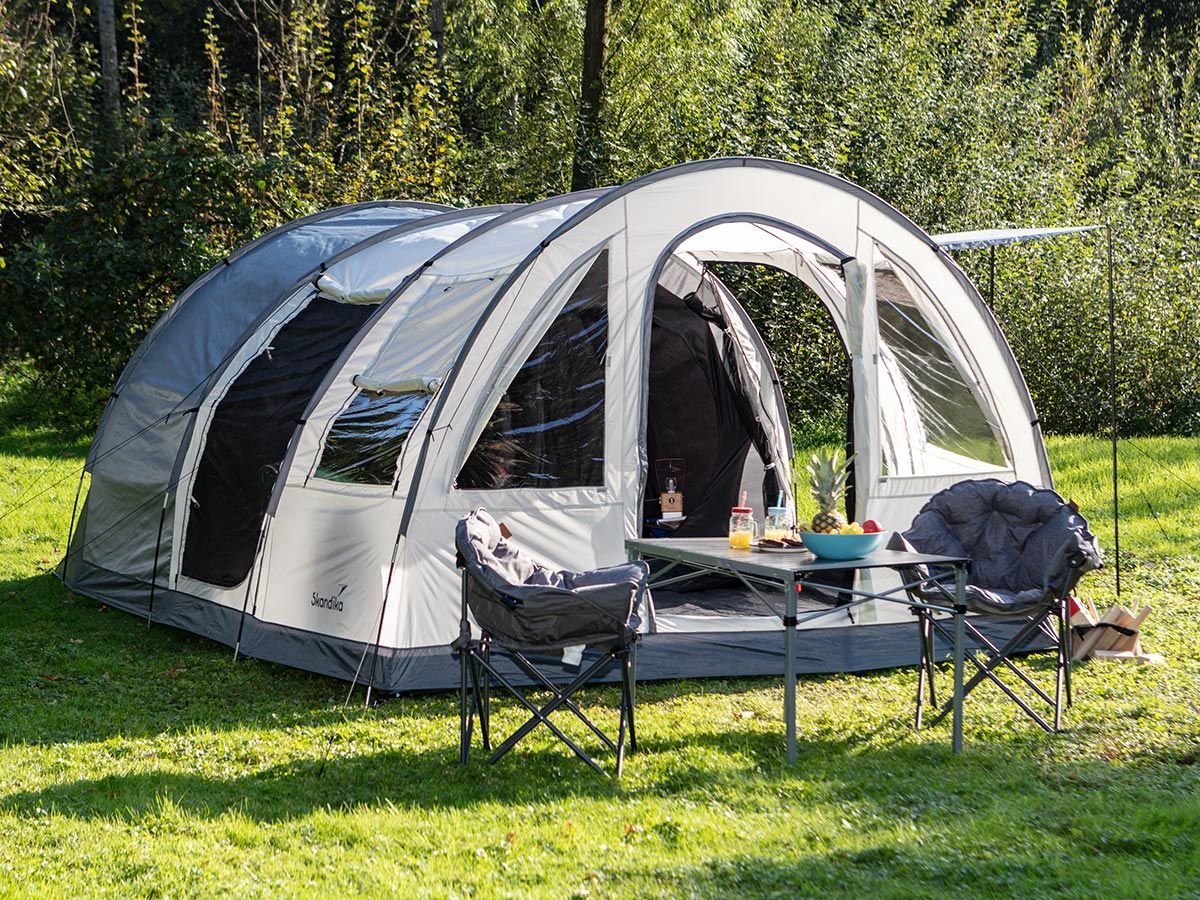 Tunnelzelt Simo 4 im Grünen mit Campingmöbeln im Vordergrund