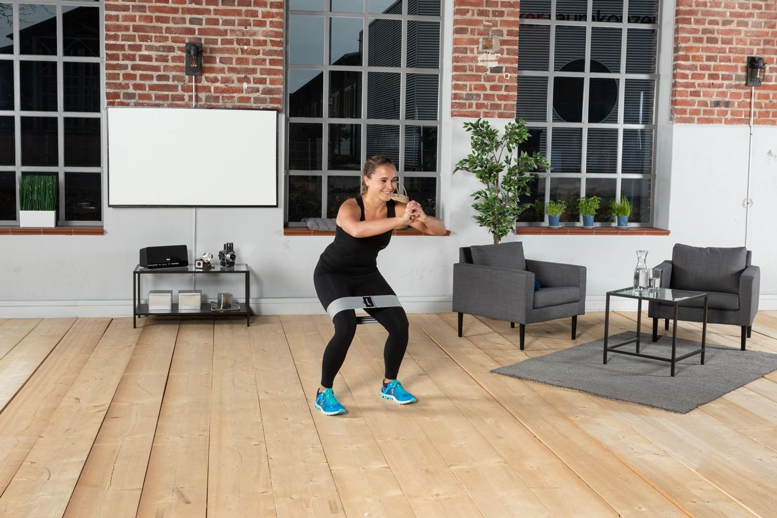 Sportlern bei Squats mit Fitnessbändern in Setting