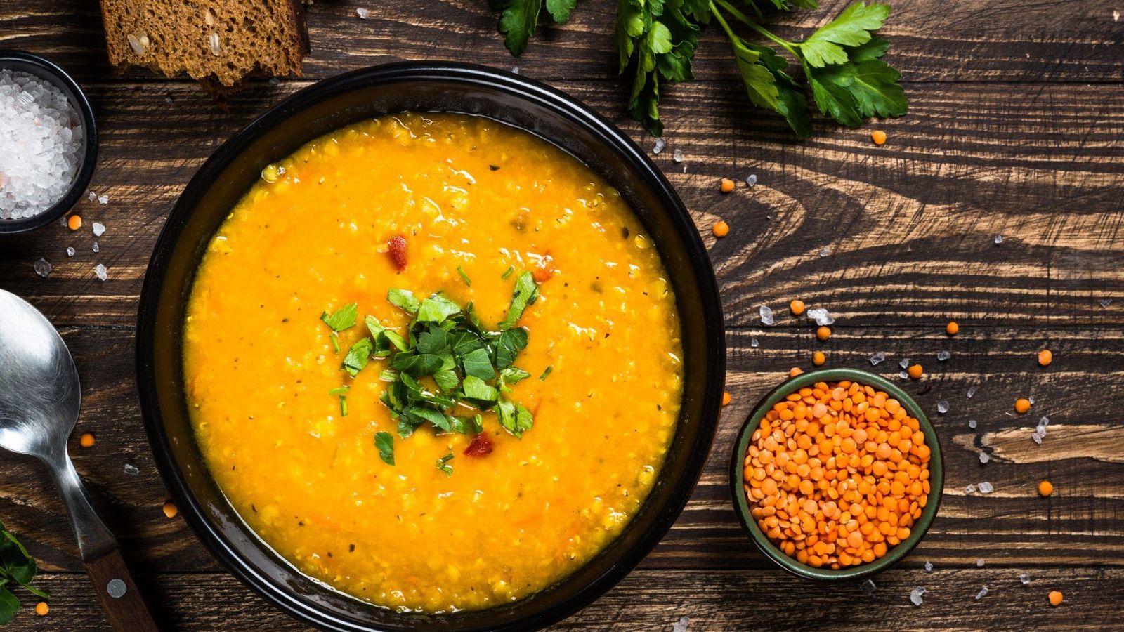 Veganes Kokos-Linsen-Curry serviert im Teller mit Scheibe Brot