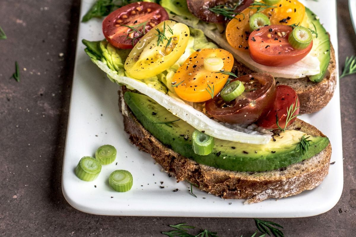 Vollkornbrot mit Avocado und Ei auf einem weißen Teller