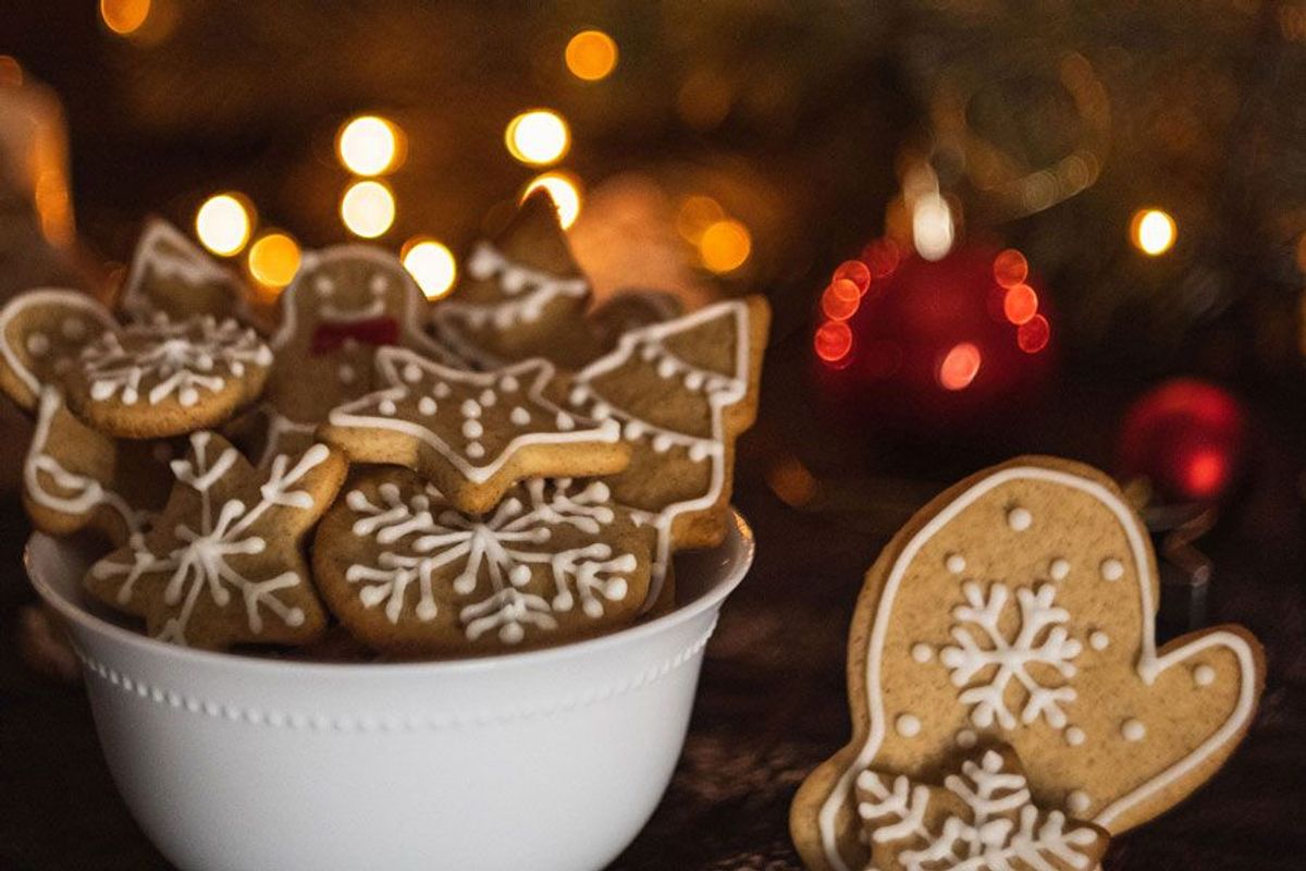 Verzierte Weihnachtsplätzchen in einer weißen Schale mit Lichtern im Hintergrund