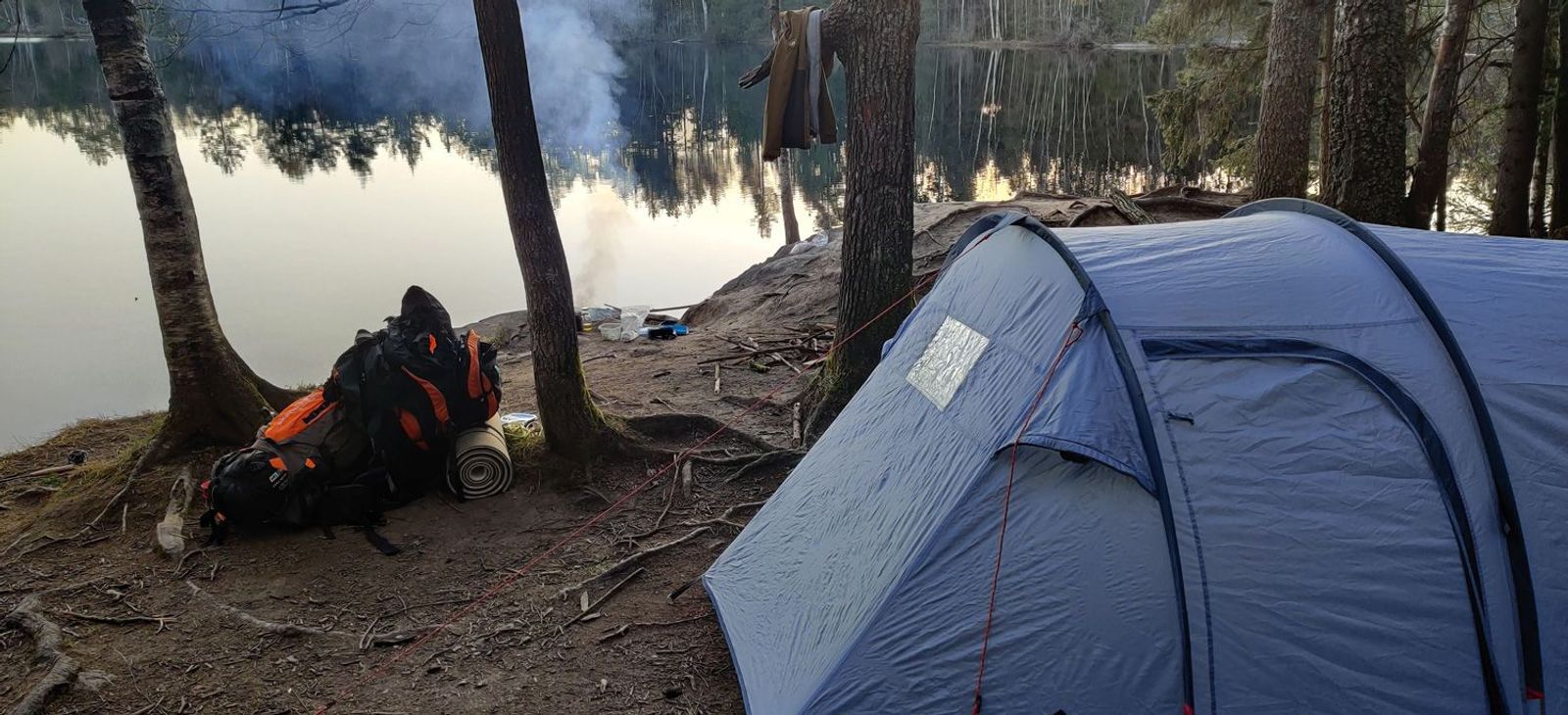 Tunnelzelt am See aufgebaut mit Lagerfeuer