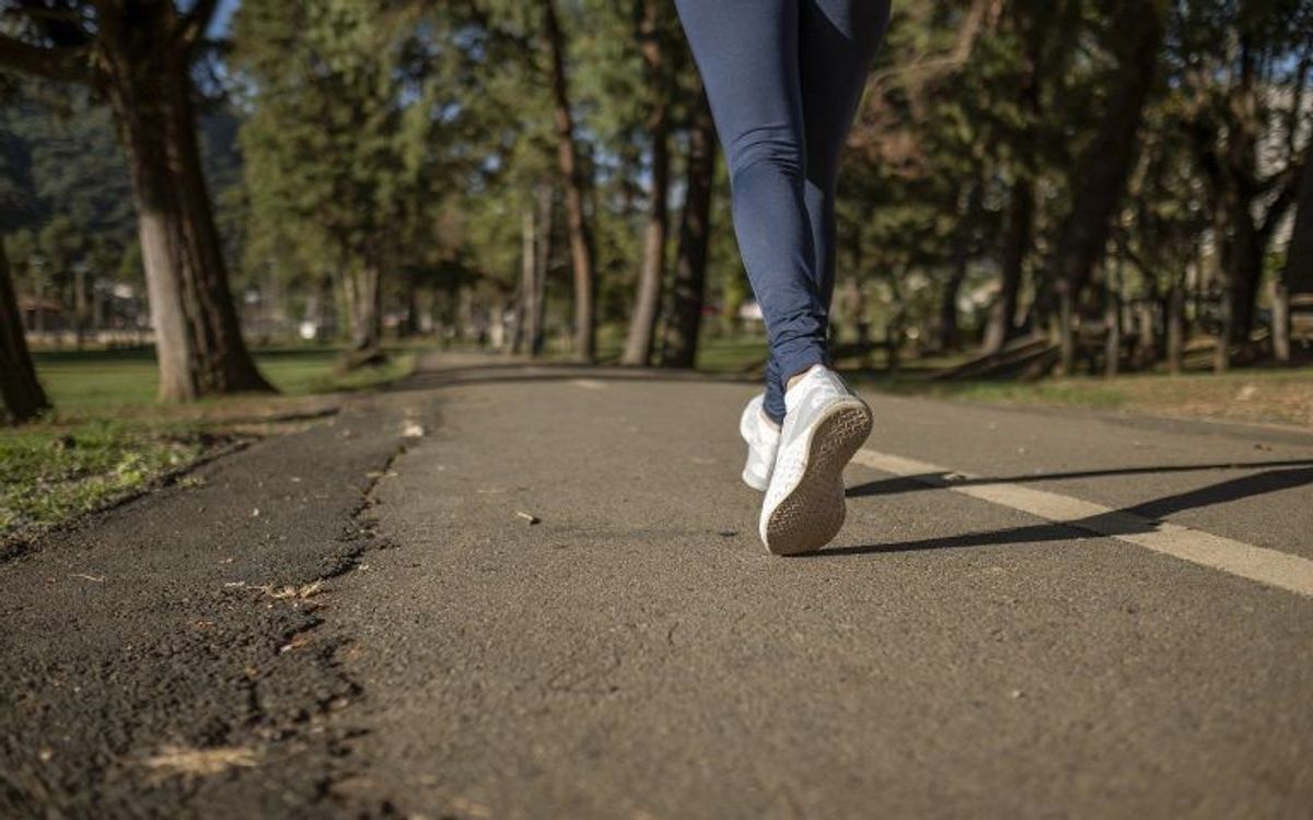 Joggerin im Park auf einem asphaltierten Weg