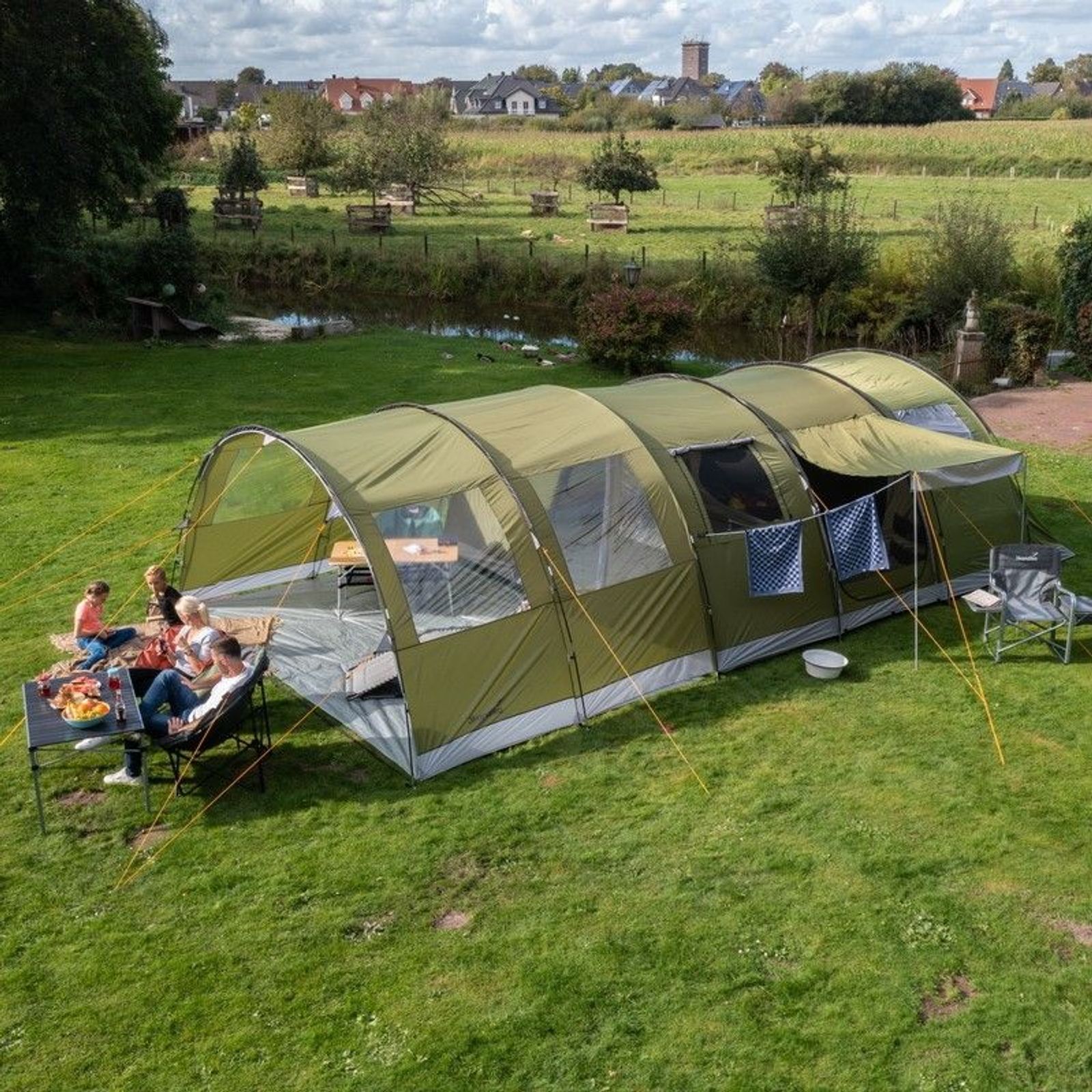 Tunnelzelt Gotland 6 mit Canopy auf einer Wiese an einem Teich aufgebaut