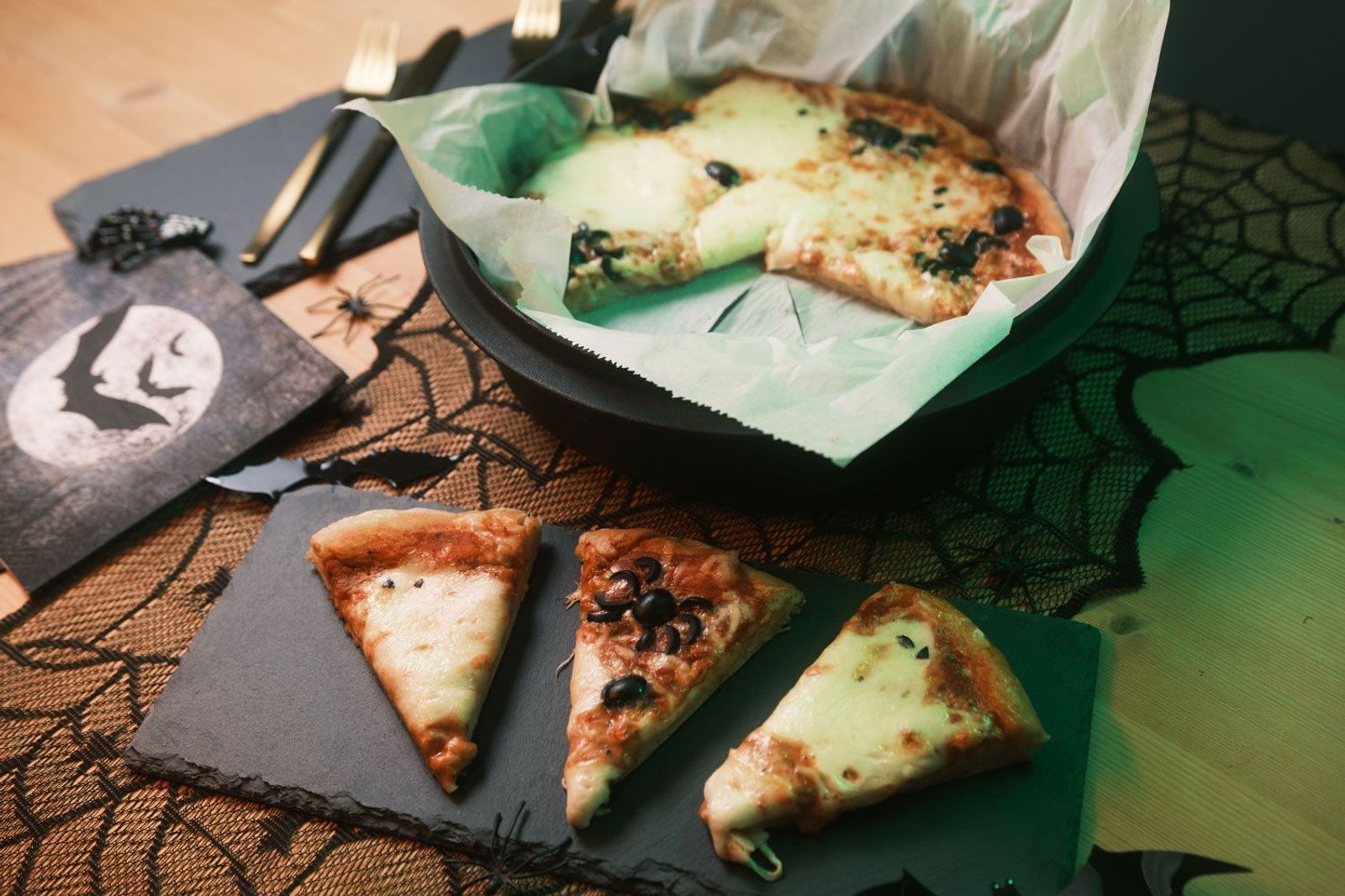 Halloween Rezept mit Mozzarella und Oliven mit Stücken auf Schieferplatte und Rest im Dutch Oven