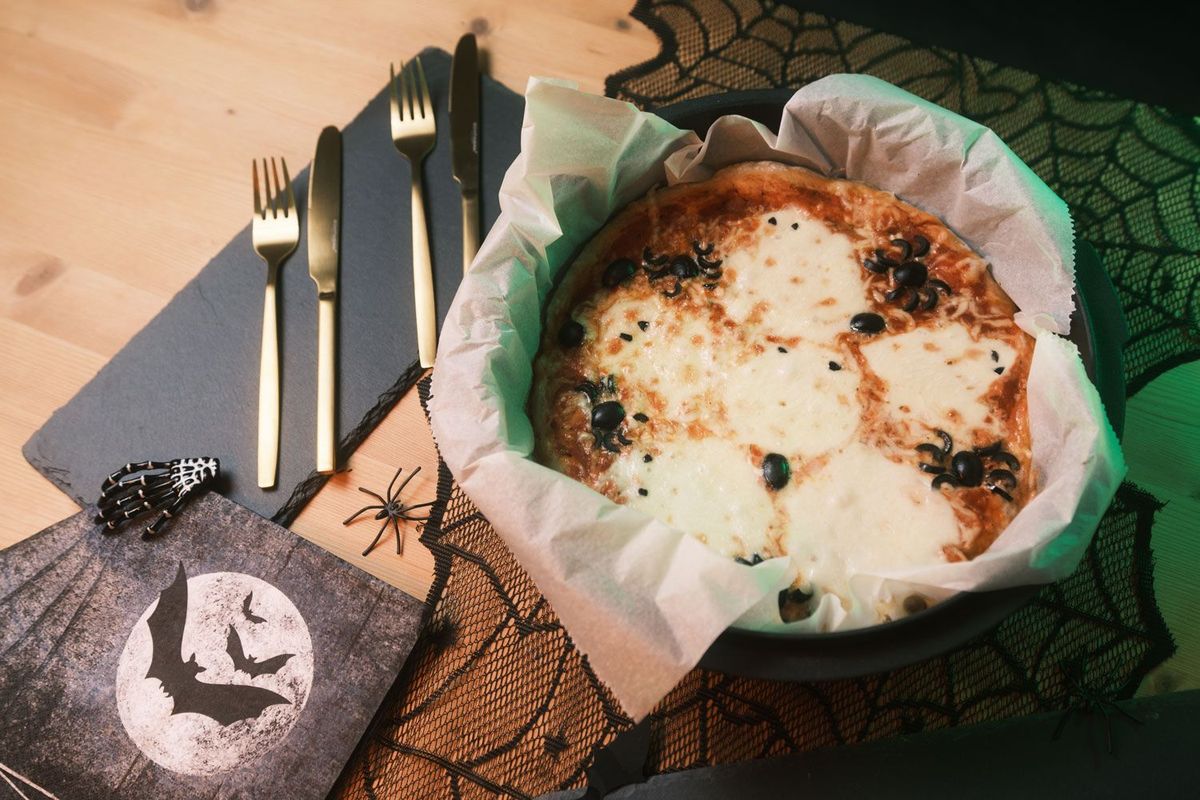 Halloween Food Pizza im Dutch Oven serviert mit goldenem Besteck und Deko