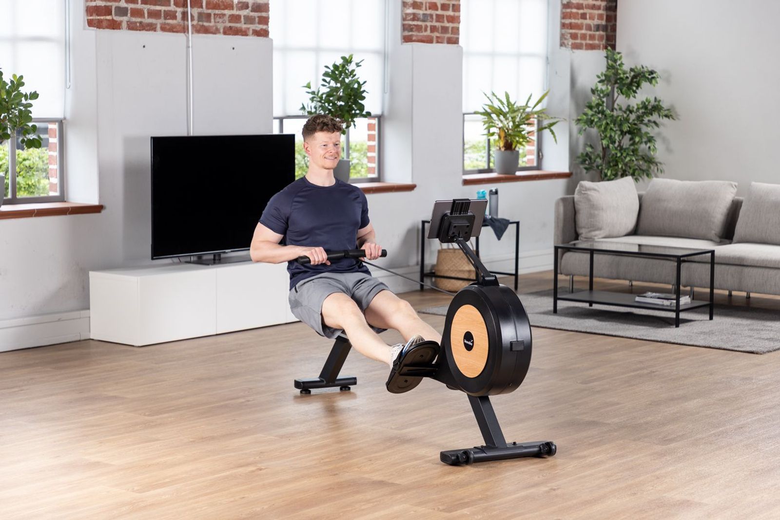 Sportler auf dem Rudergerät Njord mit Holzoptik beim Training