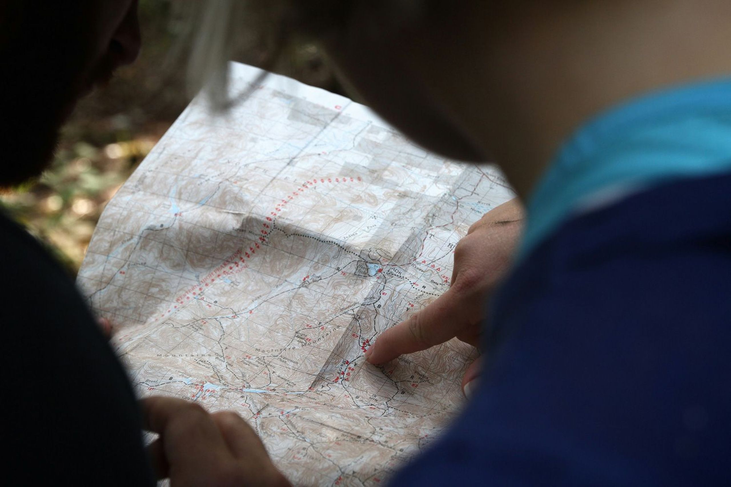 Nahaufnahme einer Wanderkarte mit einer Person, die den Finger auf die Karte zeigt